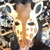 A pixelated static image shows a person with light skin and dark hair wearing a white shirt with a patterned design, set against a blurred background.