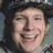 Pixelated close-up of a smiling person with dark hair against a blurred background.