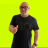 Pixelated image of a person in a black t-shirt with a dark graphic, standing against a bright yellow background, right hand raised in a gesture.