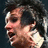 Pixelated close-up of a person with dark hair and light skin, mouth open in profile view against dark background.