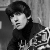 Black-and-white photograph of a person with dark hair wearing a dark turtleneck sweater, seated against a textured wall with a patterned object partially visible.