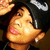 A person with short black hair and a black cap wearing small earrings, shown in four with slight head position changes