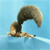 A small animal with a bushy tail lies on a light blue surface, its tail arching and curling through multiple positions.