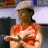 A 4-frame animated contact sheet showing a person in an orange sleeveless top and light cap performing hand gestures against a blurred background with blue and white elements.