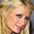 Pixelated close-up of a person with blonde hair and light skin, showing partial facial features including an eye, nose, mouth, and ear against a blurred background.