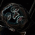 Pixelated dark icon with swirling abstract shapes in muted blues, grays, and browns against a black background.
