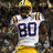 A pixelated image of a football player in a white jersey with yellow and purple accents, wearing a yellow helmet, positioned against a blurred background with yellow and gray containing text