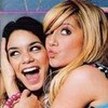 Two people in close proximity; one with dark hair and a pink bracelet, the other with blonde hair, both smiling with open mouths.