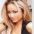 Static pixelated image of a person with long light brown hair wearing dark clothing, holding an object near their face against a light background.