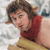 Pixelated static image of a person with brown hair wearing red and yellow clothing against a light background.