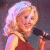 A pixelated image showing a woman with blonde hair holding a microphone on the left, and green text reading "Original Icons .com" on a dark background on the right.