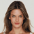 Pixelated image of a person with long brown hair, light skin, and a neutral expression against a plain light background.