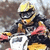 A rider in yellow helmet and goggles rides a dirt bike with red accents, captured across three showing motion