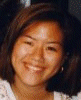 A static image of a person with shoulder-length dark hair wearing a light-colored top with a patterned design, smiling at the camera.