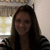 A static pixelated image shows a person with long dark hair wearing a black and white striped top against a light-colored wall with a blurred background element.