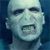 Static pixelated image of a pale humanoid face with dark eyes and mouth, set against a blue background.