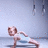A person in a light blue sleeveless top performs push-ups on a gray floor with hanging rings visible against a pale wall.