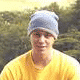A person in a yellow shirt and light blue beanie appears with a patterned cap moving across the top of their head, then resting on it.