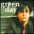 A pixelated image split into two sections: left shows a person in green clothing with orange hair and pink tie, right displays 'GREEN DAY' text below circular logo.