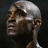 Pixelated grayscale portrait of a bald man with dark skin, visible ear, and closed mouth expression against dark background.