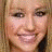 A pixelated close-up of a smiling person with light brown hair, featuring a small white heart symbol near the bottom center.