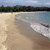 Pixelated beach scene with sandy shore, calm water, and distant tree line under light blue sky.