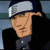 Pixelated image of a person wearing a white cap and dark clothing with a blurred background.
