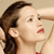 Pixelated close-up of a person with dark brown hair tied back, light skin, red lips, and a red garment visible at the bottom right.