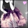 A pixelated image shows a person with long purple hair wearing a black top and striped pants, with a pink heart symbol in the top right corner.