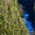 A pixelated static image with a dense green and brown textured background transitioning to a dark blue area with scattered bright blue pixels.
