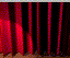 Red stage curtains part to reveal a black-and-white clapperboard under blue spotlight on brown floor.