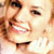 Pixelated close-up of a smiling person's face with visible eyes, nose, mouth, and hair in warm tones.