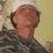 Pixelated image of a person in military uniform with short brown hair, light skin tone, and closed eyes against a pale yellow background.