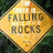 Yellow background with black pixelated text and a diamond-shaped road sign reading 'FALLING ROCKS' on the left.