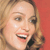 Pixelated close-up of a smiling person with light brown hair against a solid red background.