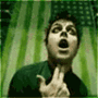 A person in a dark green shirt against a green striped background with a checkered pattern, showing sequential mouth and hand movements.