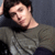Pixelated image of a person with dark hair wearing a gray shirt, head tilted back against a gradient background.