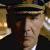 Pixelated close-up of a person wearing a dark hat and dark clothing, with a blurred background containing light and dark tones.