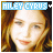 A pixelated image of a person with long brown hair, light skin, and blue eyes. The text "HILEY CYRUS" appears in the top-left corner.