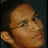Pixelated close-up of a person's face with closed eyes, light brown skin tone, and visible ear against dark background.