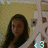 A pixelated static image shows a person with long dark hair against a textured beige background, wearing a white top and holding an object with blue accents.