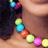 A pixelated image shows a string of colorful, round beads in blue, red, green, and pink against a dark and light brown background.