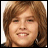 Pixelated close-up of a person with light brown hair, closed eyes, and visible teeth in a neutral expression against a white background.