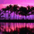 Pixelated landscape with purple and pink sky reflecting in water, dark silhouetted trees along the horizon.