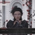 A pixelated static image shows a person with dark hair wearing a dark top, positioned against a light background with vertical elements.