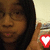 A person with long dark hair and glasses holds a hand near their face, displaying heart-shaped icons that change color across frames.