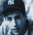 Pixelated static image of a person wearing dark cap with white text, light-colored shirt, and dark jacket against blue-gray background.
