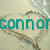 Pixelated teal text 'Connor' overlaid on a blurred background with abstract brown and gray shapes.