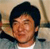 A pixelated close-up of a person with dark hair wearing a light-colored shirt against a blurred background.
