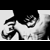Static black-and-white pixelated icon showing a stylized figure with exaggerated facial features and flowing hair against a light background.